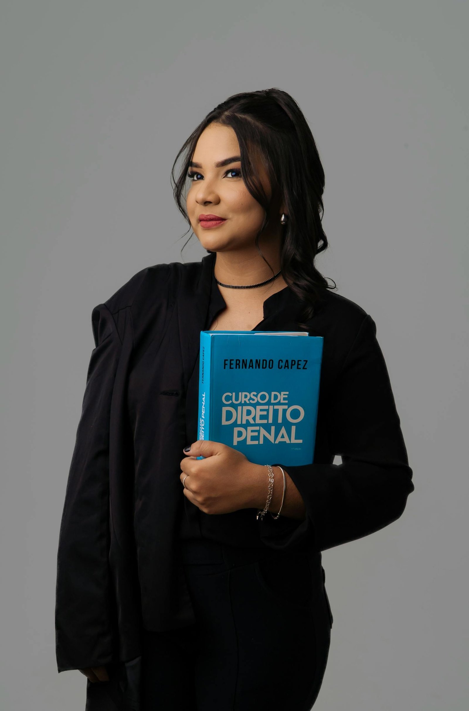 Confident woman posing with a law book against a neutral background. Ideal for educational or legal themes.
