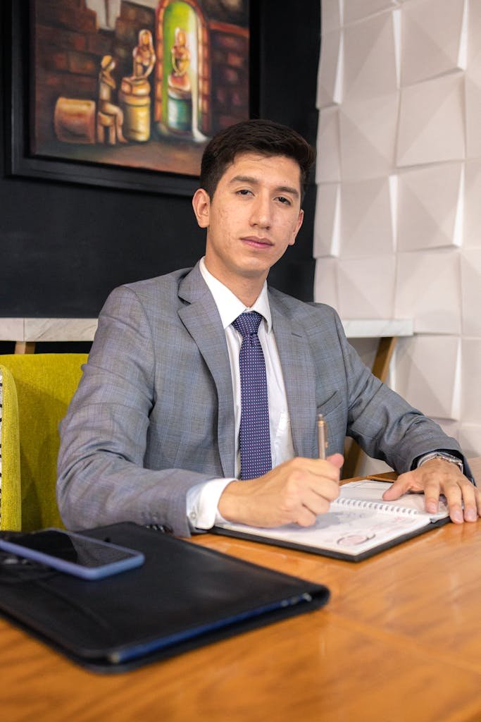 Professional businessman in a gray suit working at a desk with a notebook and pen.